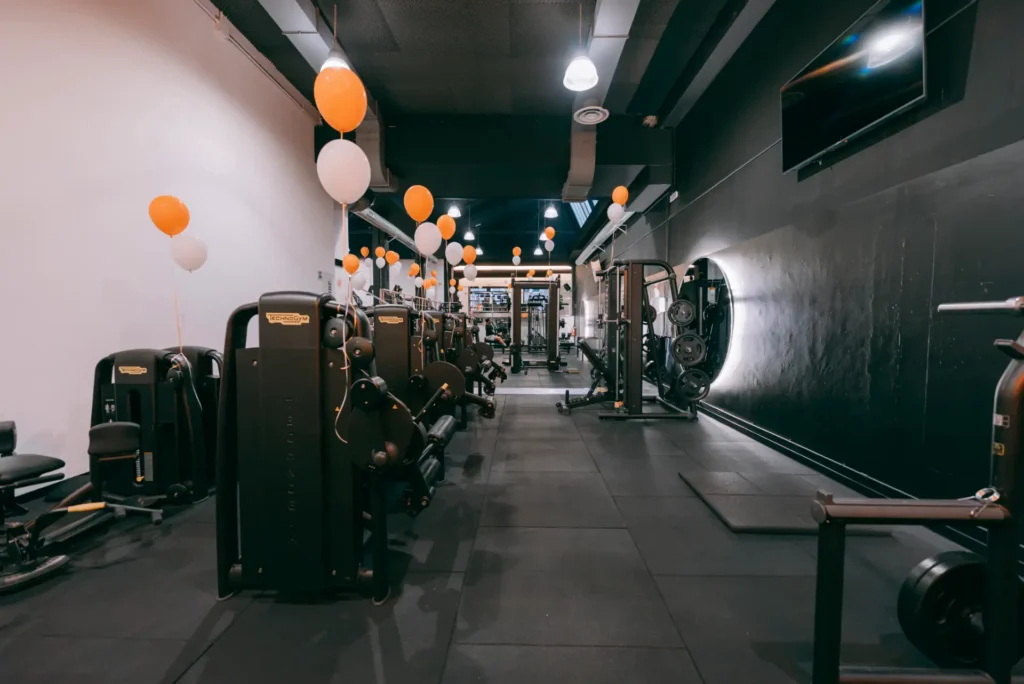 Navata centrale della palestra Vibe Fitness ad Arcore con fila di macchine isotoniche Technogym e parete con specchi retroilluminati